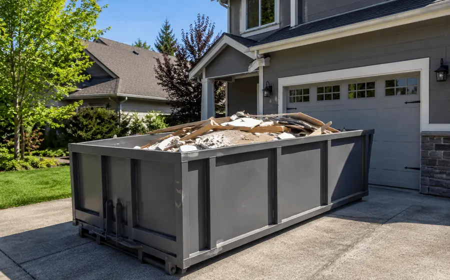 Roll-off dumpster full of construction and renovation debris in front of a suburban home